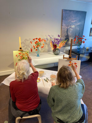 Vrouwen die een bloemstilleven schildert tijdens een workshop